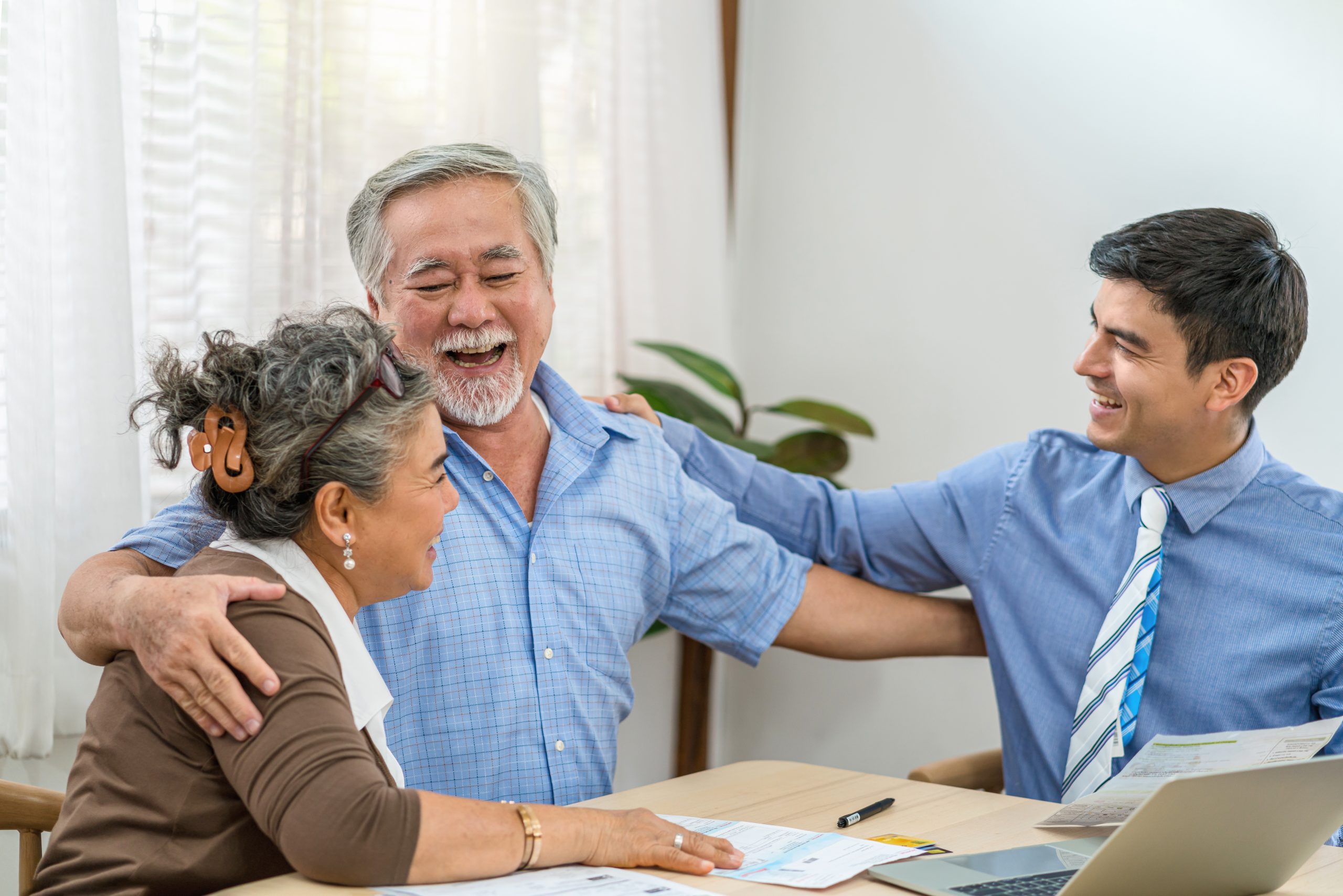 Asian couple grandparent are happy with insurance agency manager after deal the agreement successful, financial planner presenting and Closing the sale of real estate, document and bill with laptop